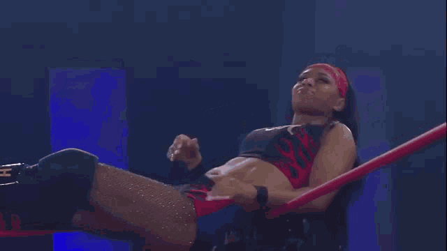 a woman is laying in a wrestling ring with a red rope around her waist .