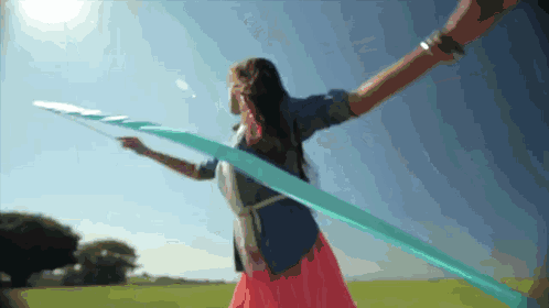 a woman in a pink dress is holding a blue ribbon in a field