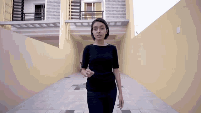 a woman in a black shirt is standing in front of a house
