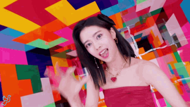 a woman in a red strapless dress is dancing in front of a colorful background