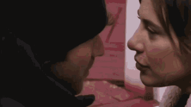 a man and a woman are kissing each other in front of a red and white wall .