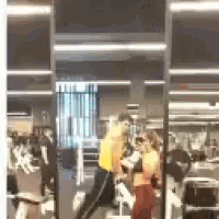 a group of people are standing in a gym looking at their reflection in a mirror .