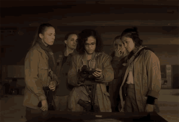 a group of women are standing around a table with a woman holding a gun