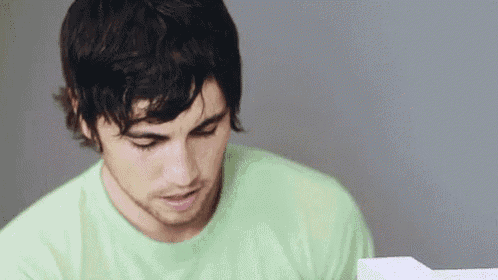 a man in a green shirt is looking down at something