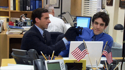 two men are sitting at a desk with an american flag on the desk