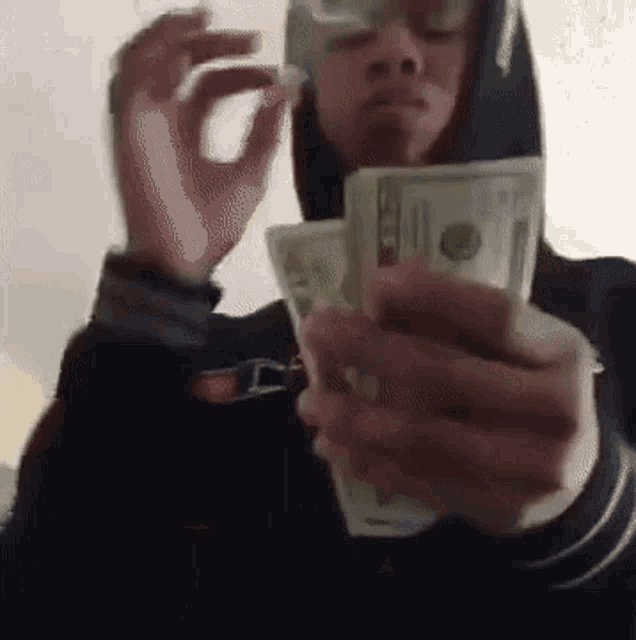 a man is smoking a cigarette while holding a stack of money .