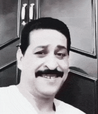 a black and white photo of a man with a mustache and missing teeth
