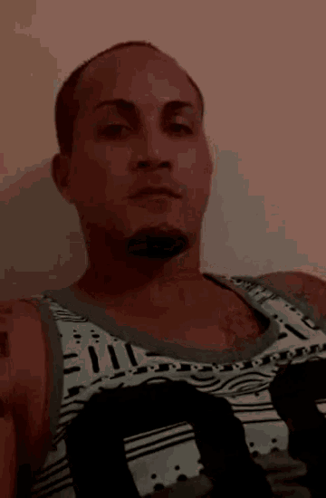 a man wearing a tank top with the number 10 on it looks at the camera