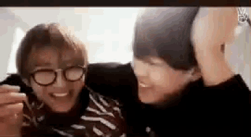 two young men wearing glasses are hugging each other on a screen .