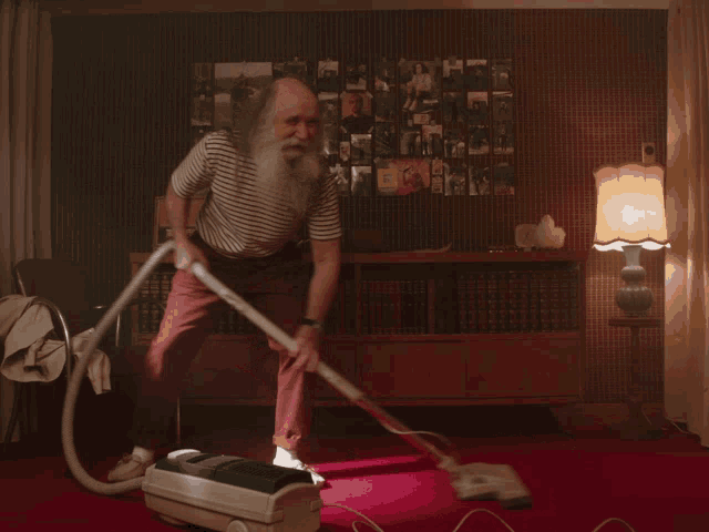 a man with a beard is vacuuming the floor