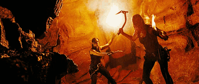 two women are fighting in a cave with a torch in their hands