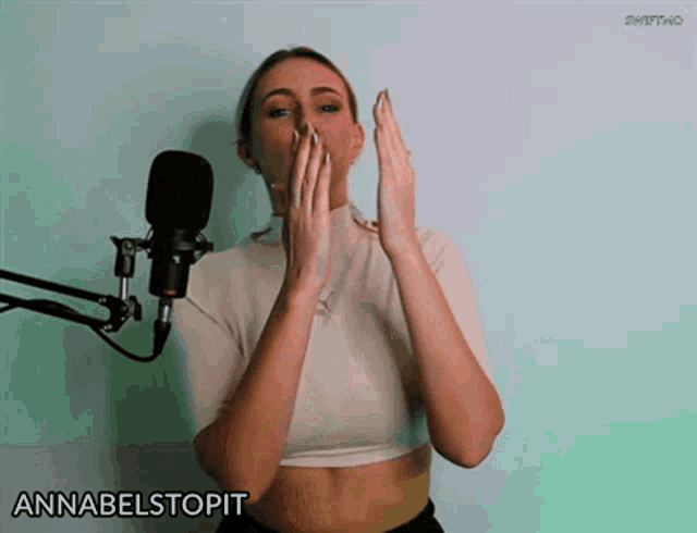 a woman covering her mouth in front of a microphone with the word annabelstopit written on the bottom