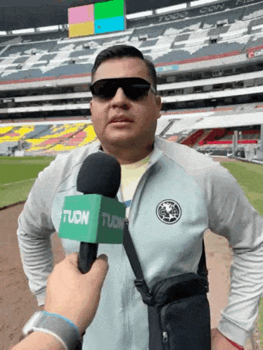 a man wearing sunglasses is being interviewed with a green microphone that says tudn