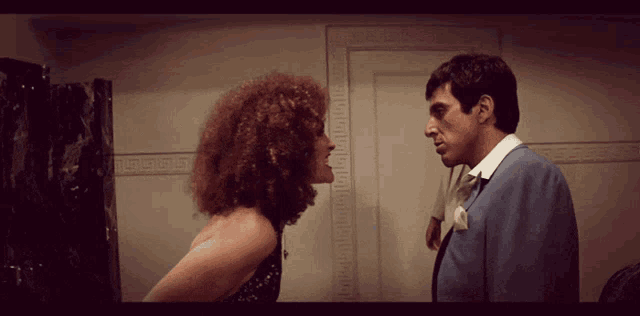 a man and a woman are looking at each other in a room with a greek key pattern on the wall