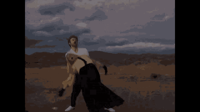 a man and a woman are dancing in a desert .