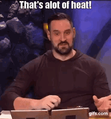 a man with a beard is sitting at a table with a laptop and a tablet .