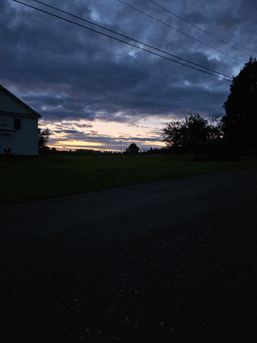 a sunset over a field with a white building in the foreground and a sign that says ' sunset ' on it