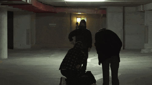 a group of people are standing in a dark parking garage