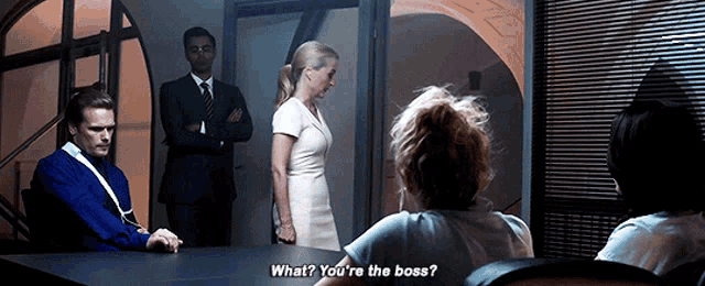 a group of people are sitting around a table and one of them is asking what ? you 're the boss ?