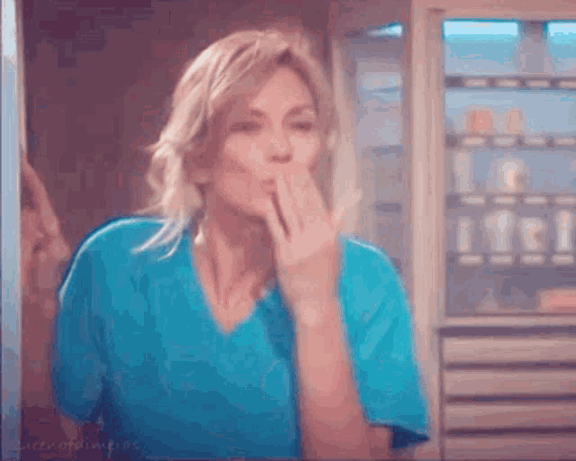 the woman is wearing a blue scrub top and blowing a kiss .