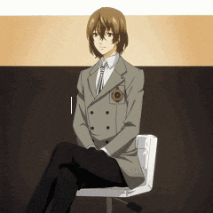 a man in a suit sits on a chair with his legs crossed