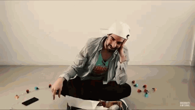 a man sitting on the floor talking on a cell phone with a box of candy in the background