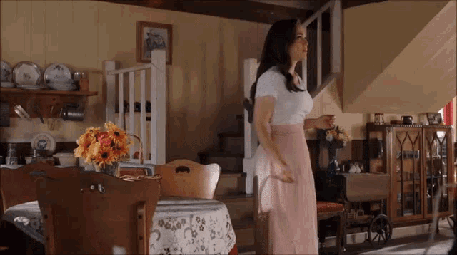 a woman in a pink skirt is standing in front of a table