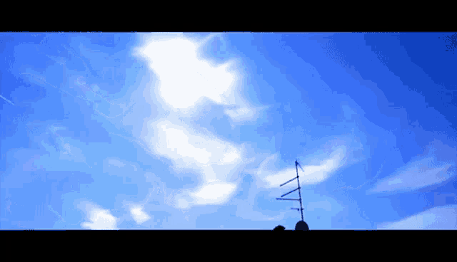 a blue sky with white clouds and an antenna