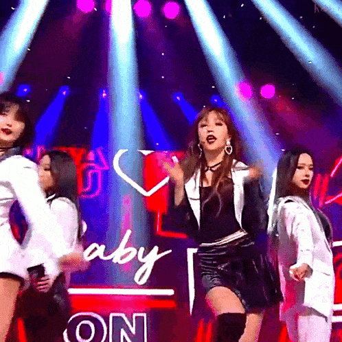 a group of women are dancing on a stage in front of a sign that says baby