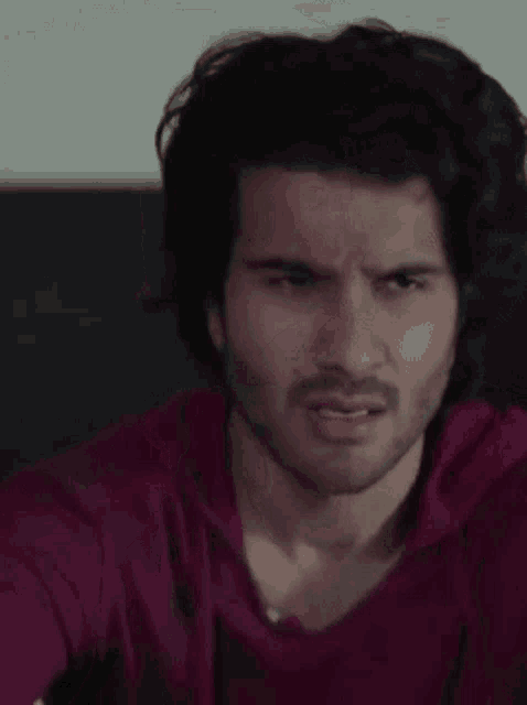 a man with a beard and long hair is making a funny face .