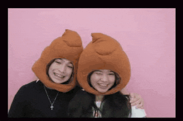 two girls are posing for a picture while wearing funny hats .