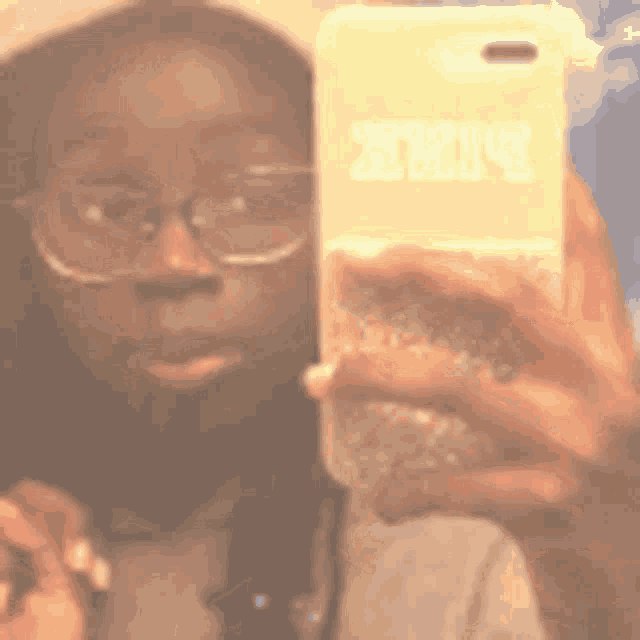 a woman wearing glasses is taking a selfie with a phone case that says pink