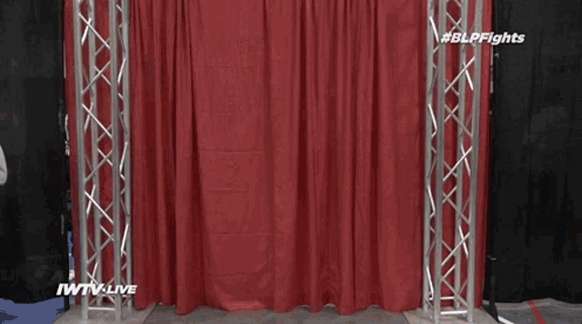 a man is running through a red curtain that says iwtv live on it
