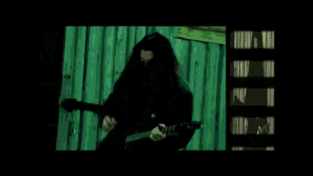 a green screen with a blurred image of a person standing in a dark room .