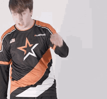 a man wearing a black and orange shirt with a white star on it is dancing .
