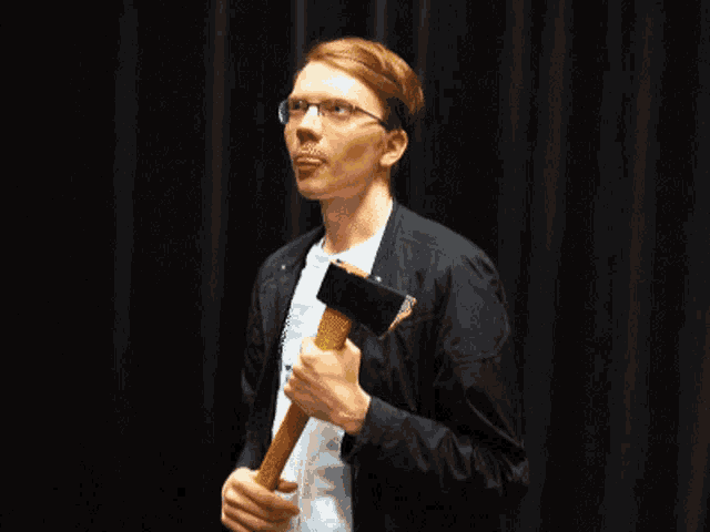 a man wearing glasses is holding a hammer