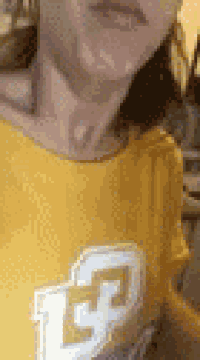 a close up of a person wearing a yellow t-shirt with a white l on it .