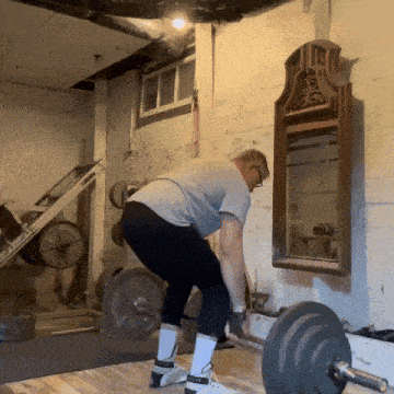 a man lifting a barbell in front of a mirror