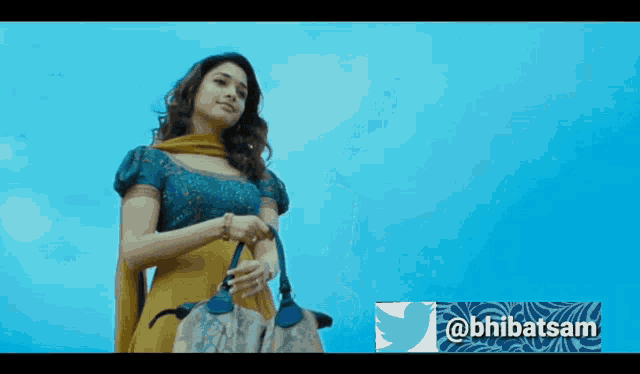 a woman in a yellow dress is holding a purse in front of a twitter icon