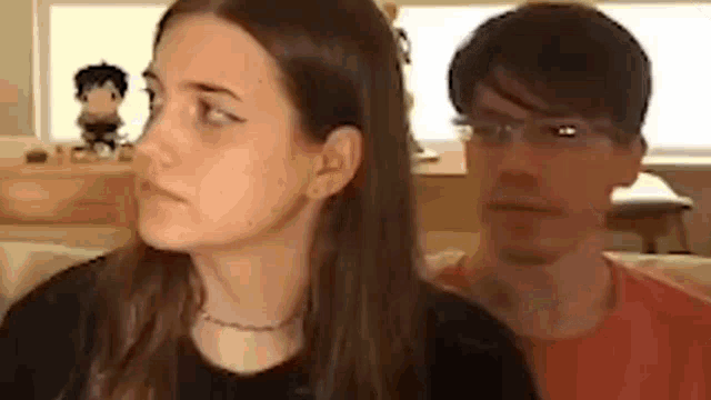 a man and a woman are sitting next to each other on a couch . the woman is looking at the man .