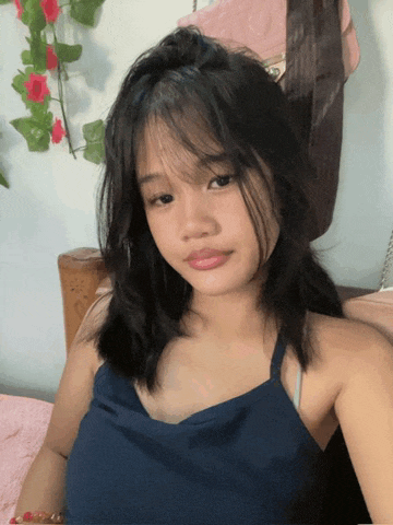 a young girl in a blue tank top is taking a selfie