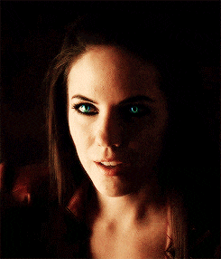a woman with green eyes is smiling in the dark