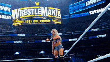a woman in a wrestling ring with a wrestlemania sign in the background