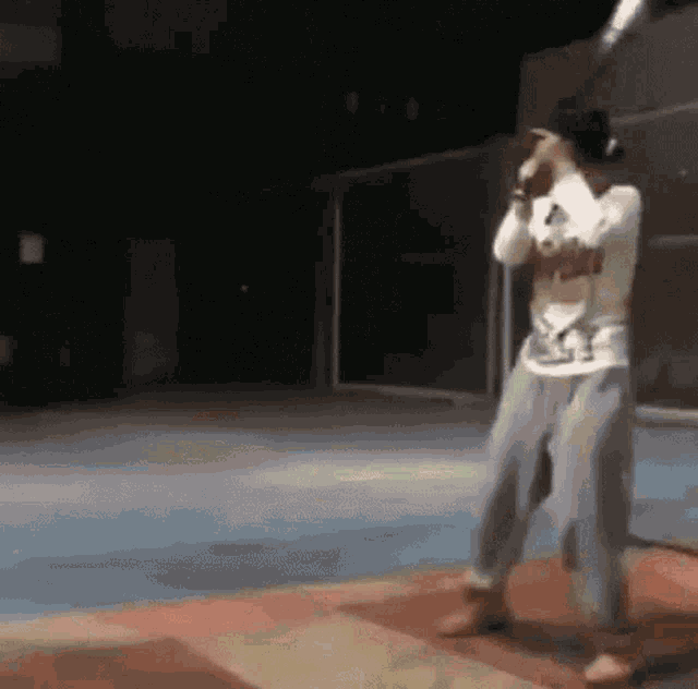 a person is dancing in a dark room with a microphone .