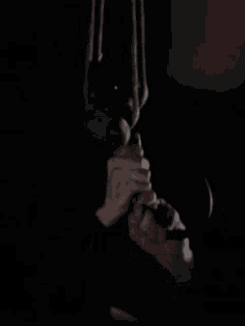 a close up of a person holding a rope in their hand in a dark room .