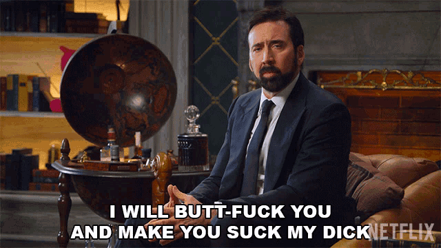 a man in a suit and tie is sitting on a couch and says i will butt-fuck you and make you suck my dick