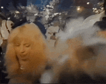 a woman with long blonde hair is dancing in a crowded room .