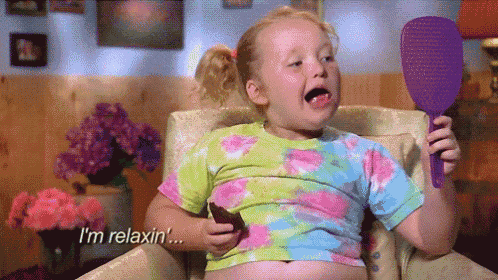 a little girl is sitting in a chair holding a mirror and saying " i 'm relaxin ' "