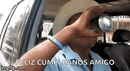 a man is drinking from a can in a car while driving .