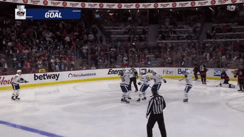 a hockey game is being played in a stadium with advertisements for betting and energy